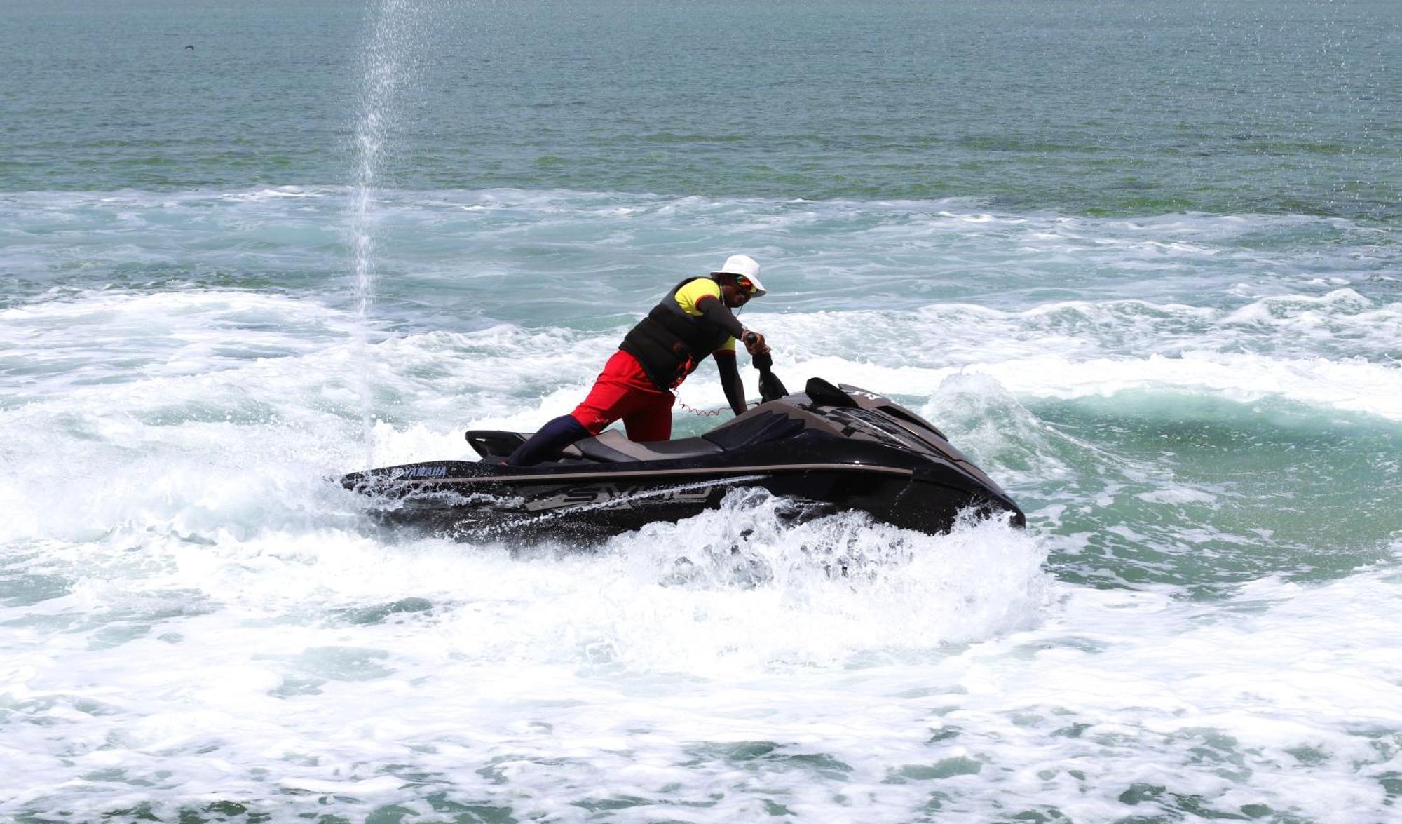 Lagoona Beach Luxury Resort And Spa Manama Exterior foto The photo shows a person riding a jet ski on the water. The rider is positioned upright, leaning forward with one hand on the handlebars, while the jet ski creates splashes of white foam around it. The water appears choppy, likely due to the motion o